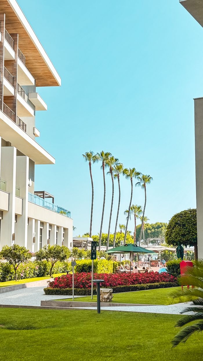 View of a luxury hotel's exterior in Antalya with palm trees and garden.