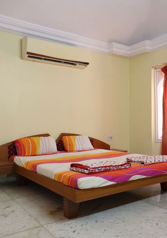 A cozy bedroom in Ahmedabad featuring a double bed with vibrant bedding.