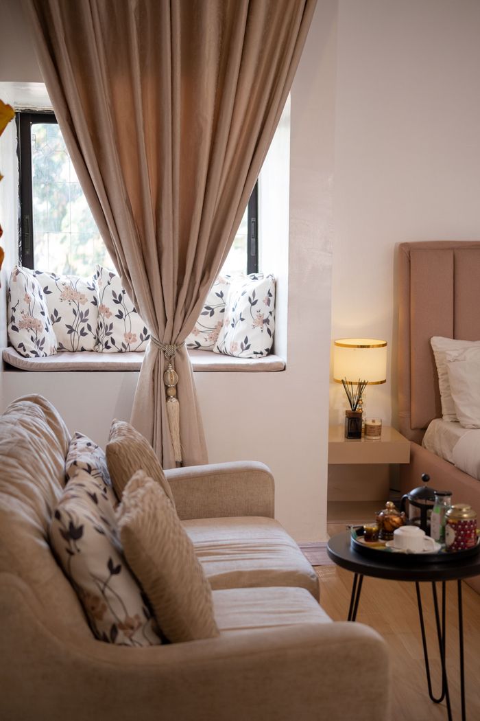 Stylish living room interior featuring beige sofa, floral cushions, and elegant curtains.