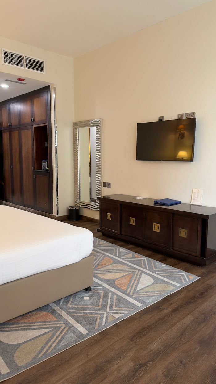 gallery-05 A spacious hotel room with modern decor, featuring a TV and elegant furnishings.